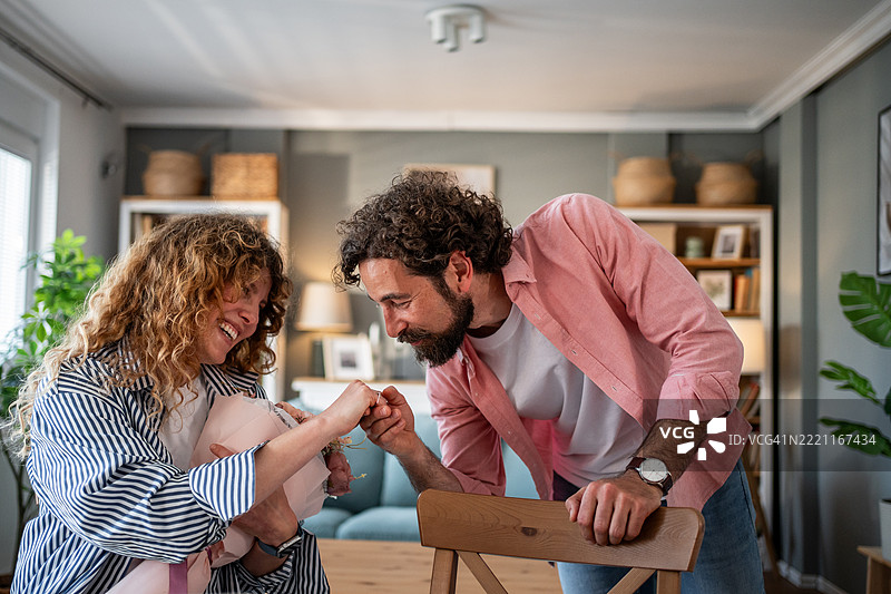 快乐的父母在家中握着新生儿的手图片素材