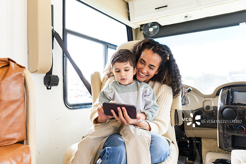 快乐的母亲和儿子在房车中使用平板电脑图片素材