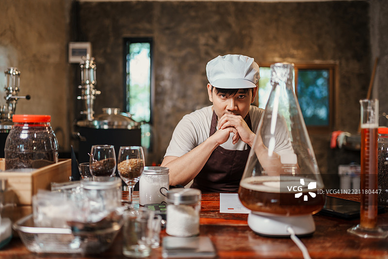 亚洲家庭酿酒师认真观察磁力搅拌器上的酵母培养液，周围是酿酒原料，正在进行手工啤酒酿造过程。图片素材