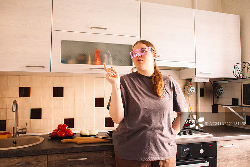 年轻女性在家厨房里戴着智能眼镜。图片素材