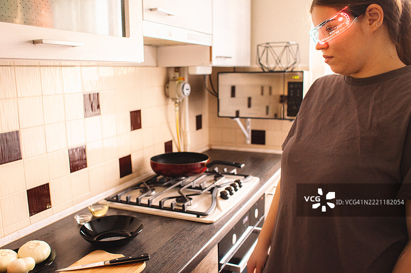 年轻女性在家厨房里戴着智能眼镜。图片素材