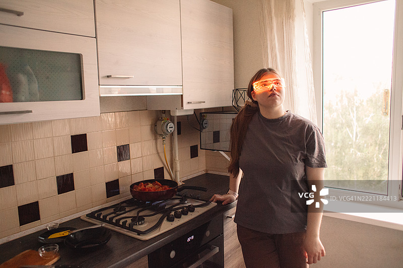 年轻女性在家中烹饪时使用智能眼镜图片素材