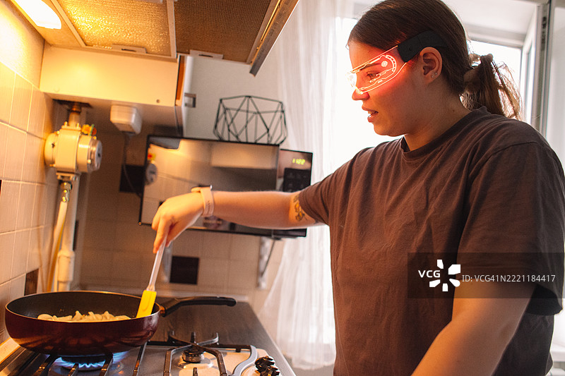 年轻女性在家中烹饪时使用智能眼镜图片素材