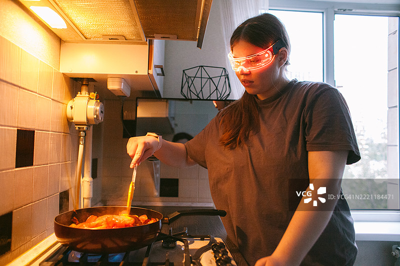 年轻女性在家中烹饪时使用智能眼镜图片素材