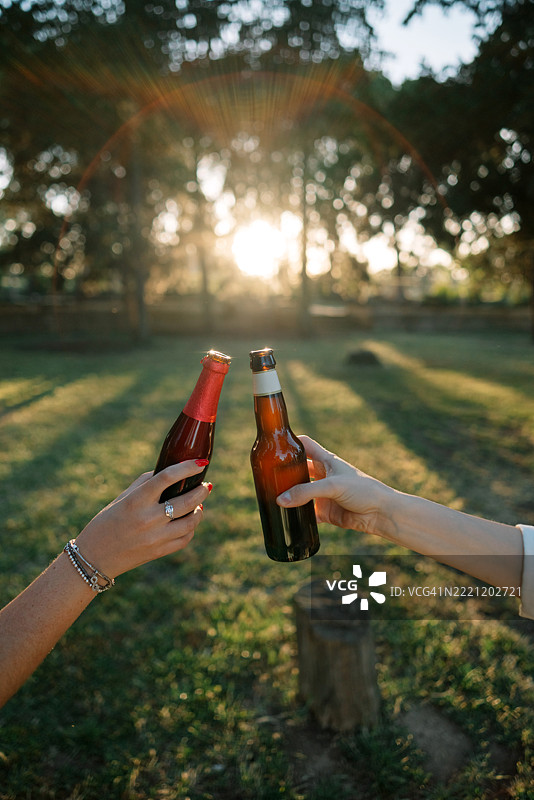 朋友们在公园里举杯庆祝，手部特写。图片素材