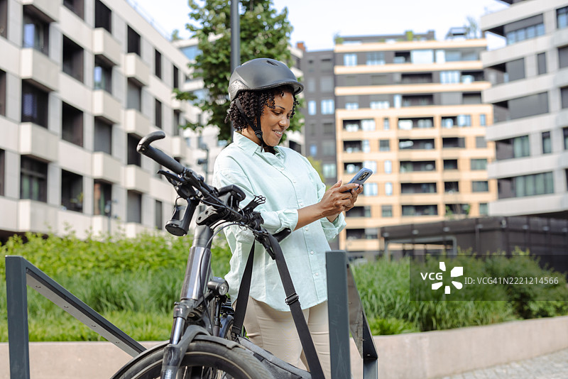 一位女性在城市建筑附近骑着自行车打电话图片素材