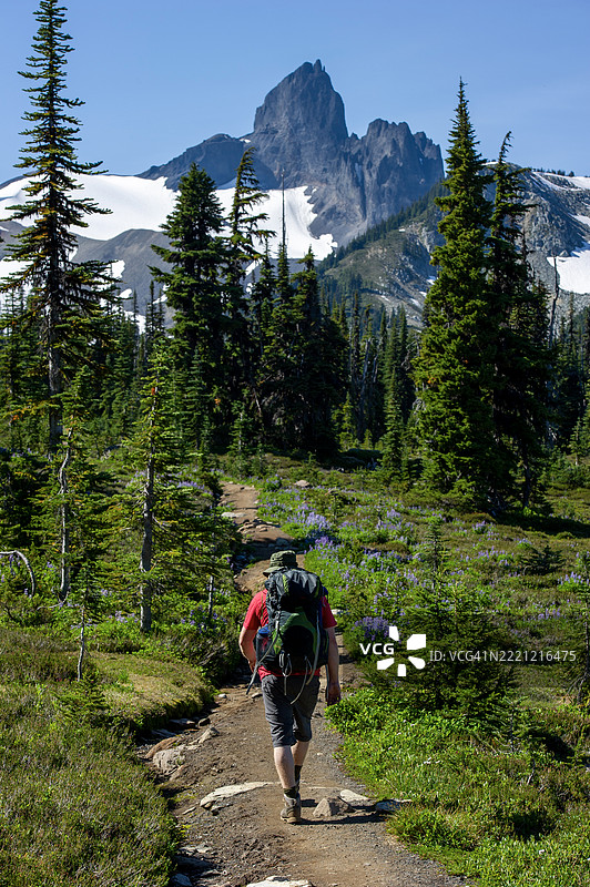 男子在山间小径上背包行走图片素材