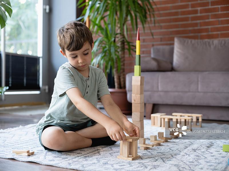 小男孩在家里独自玩木制玩具。儿童家庭活动的概念。图片素材