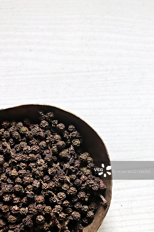 自家种植的有机黑胡椒粒特写，放在铜碗中，背景为白色/静物摄影图片素材