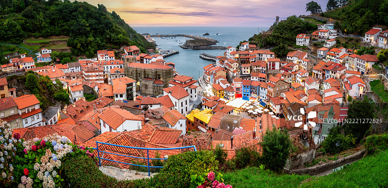 在西班牙阿斯图里亚斯的库迪列罗渔村，五彩斑斓的房屋沿陡峭的山坡层层叠叠，在金色日落的光辉下温暖地闪耀，映衬着海岸风光。图片素材