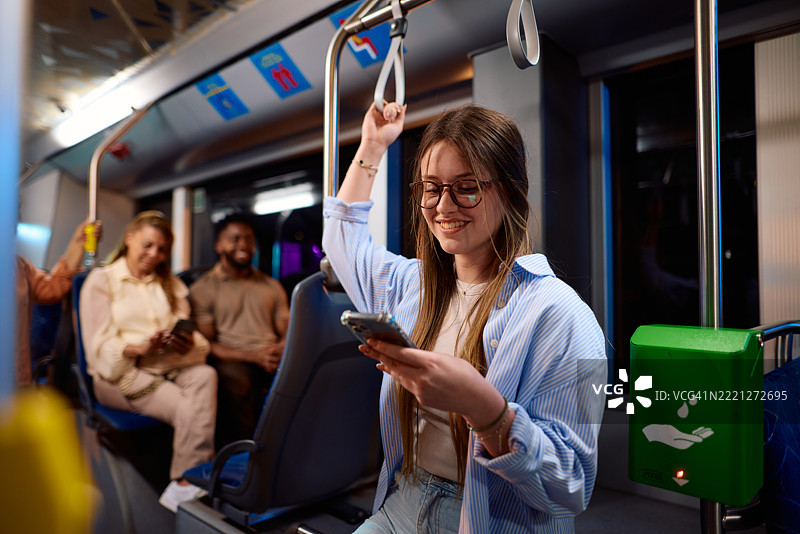 年轻女性在现代公交车或电车上使用智能手机图片素材
