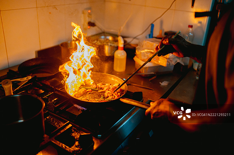 厨师在餐厅厨房用锅炒菜，火焰四射图片素材
