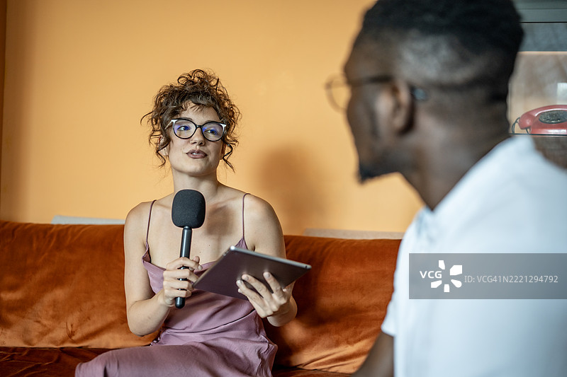 休闲的采访场景，女主持人手持麦克风和平板电脑图片素材