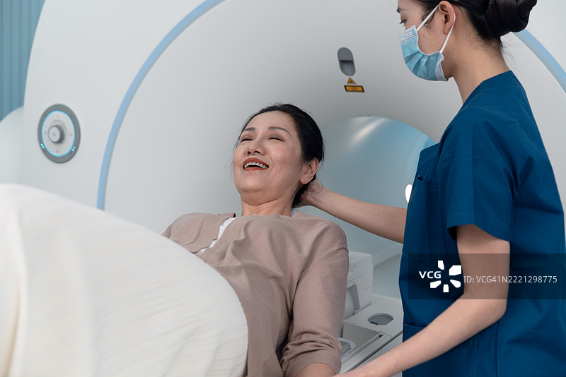 医生和护士在病房使用平板电脑分析患者的治疗状态，背景是女护士正在照顾老年患者。图片素材