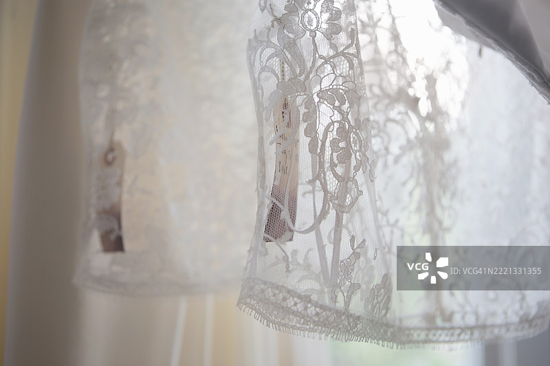 婚纱店衣架上挂着的白色蕾丝上衣特写图片素材