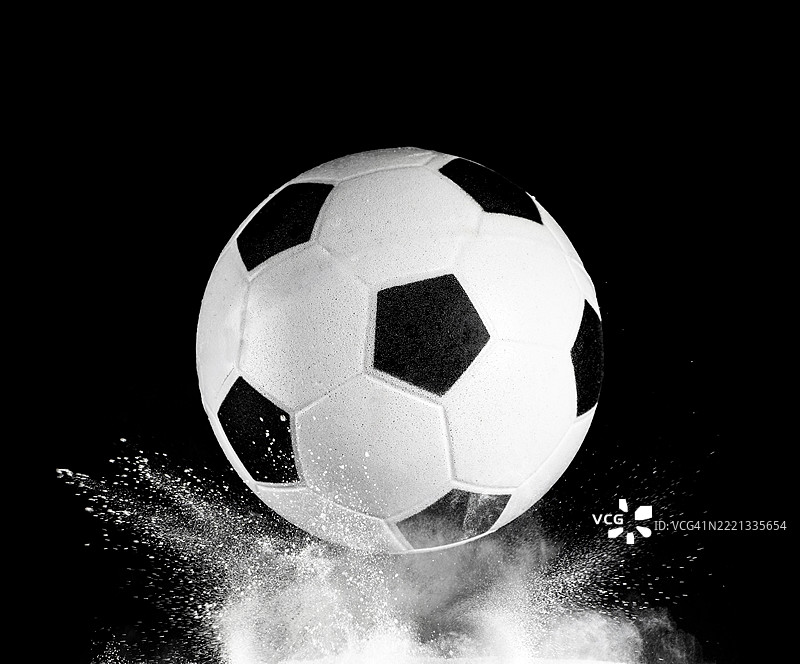 足球在黑色背景下的白色粉末表面上的撞击与反弹图片素材