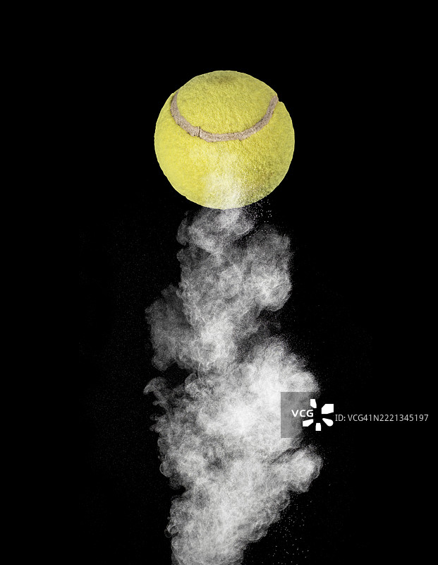 网球在黑色背景上猛烈弹跳，扬起一阵尘土。图片素材