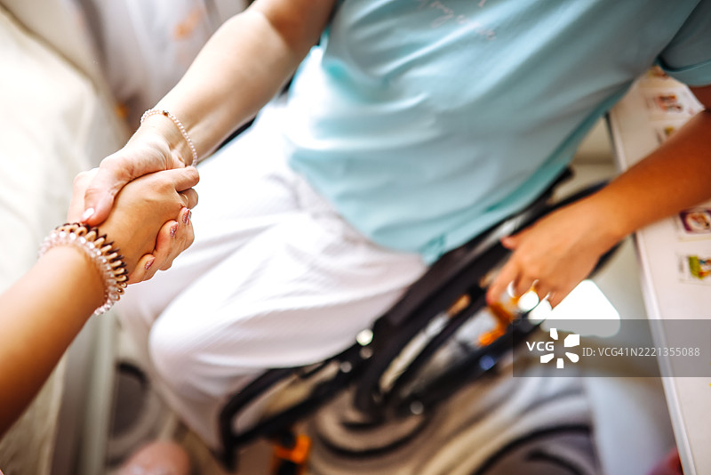 与轮椅使用者的坚定握手 - 支持的象征图片素材