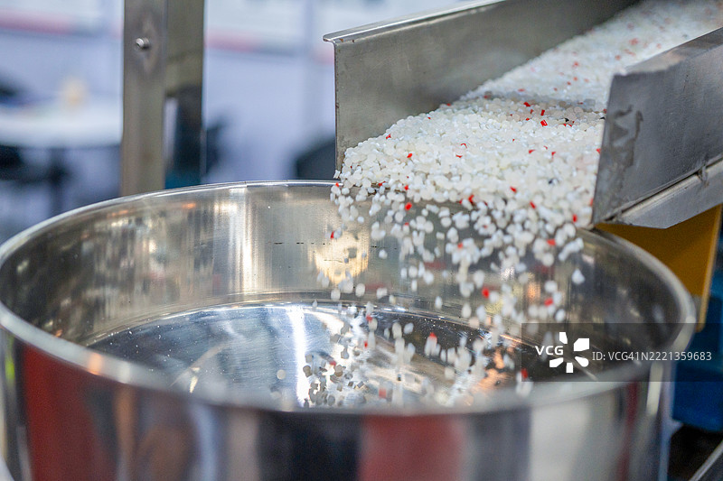 机器人手臂从注塑机进行物料搬运的过程。食品容器盒的生产过程由塑料注塑模具机完成。图片素材