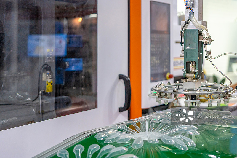 机器人手臂从注塑机进行物料搬运的过程。食品容器箱的生产过程由塑料注塑模具机完成。图片素材