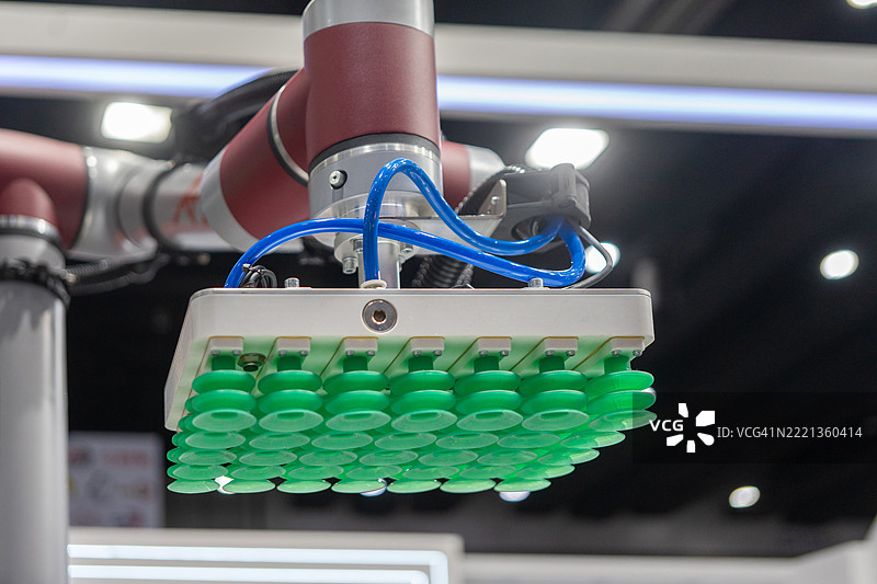 特写镜头展示小型机器人手臂操控小白巧克力板作为样品在工业建筑内移动。图片素材