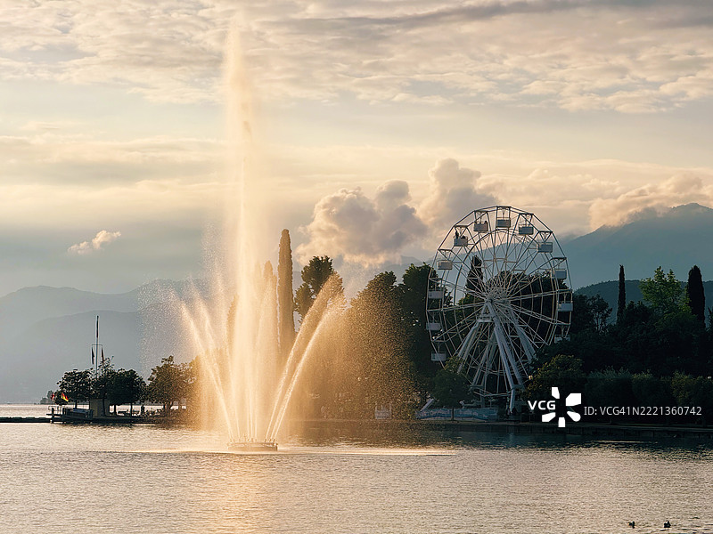 意大利加尔达湖巴尔多利诺的湖边喷泉和摩天轮在日落时分图片素材