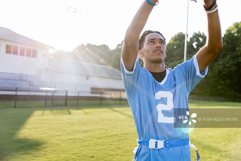 高中运动员在体育场的旗帜橄榄球比赛中跃起接球图片素材