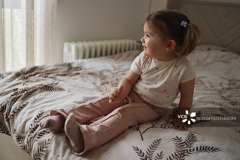 美丽微笑的女孩坐在卧室里图片素材