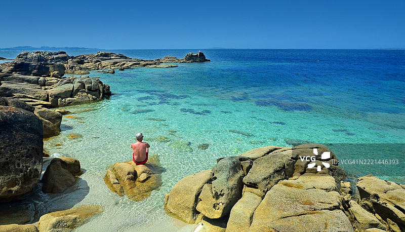 一位单身男子在西班牙加利西亚省庞特维德拉的卡雷龙自然公园内，阿罗萨岛南部美丽的海湾中享受阳光和海滩的一天。图片素材