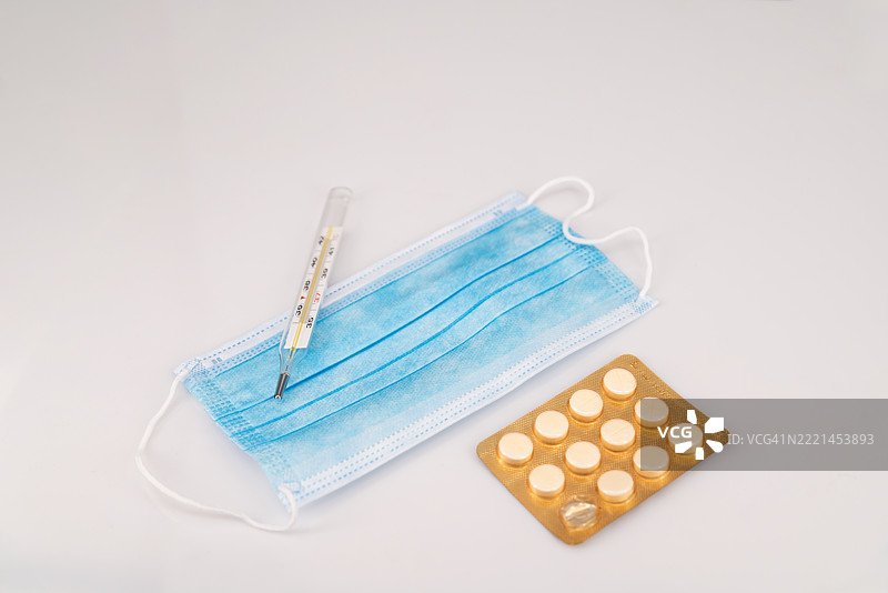 白色背景上的药丸、温度计和口罩。图片素材