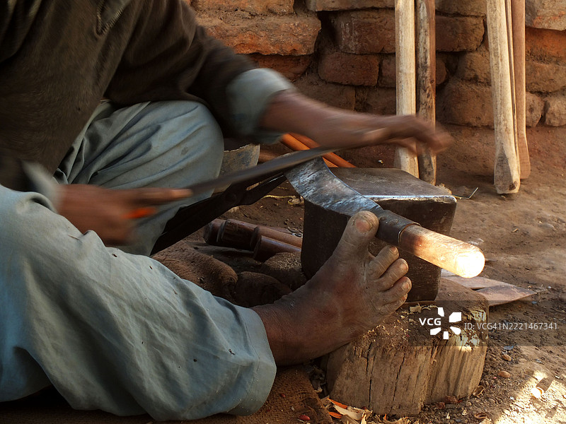 路边摊旁的铁匠与家人一起工作图片素材