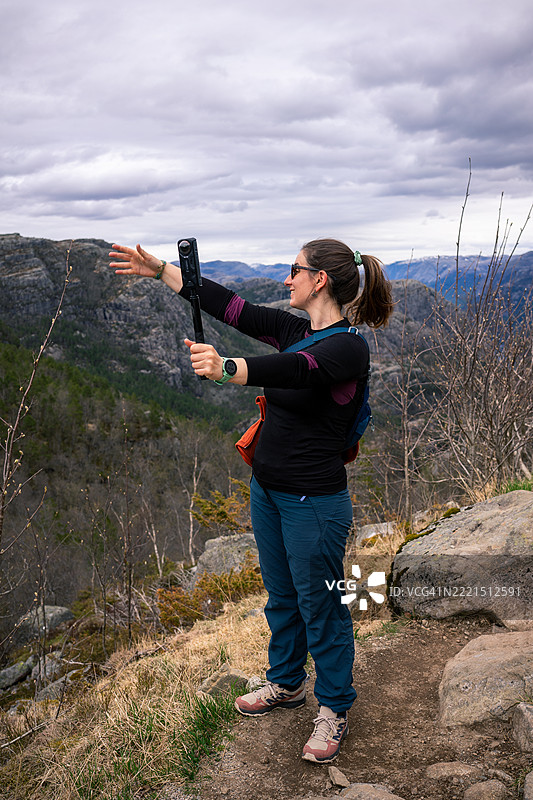在挪威普雷凯斯托伦的女性徒步旅行者使用360度相机进行视频博客图片素材