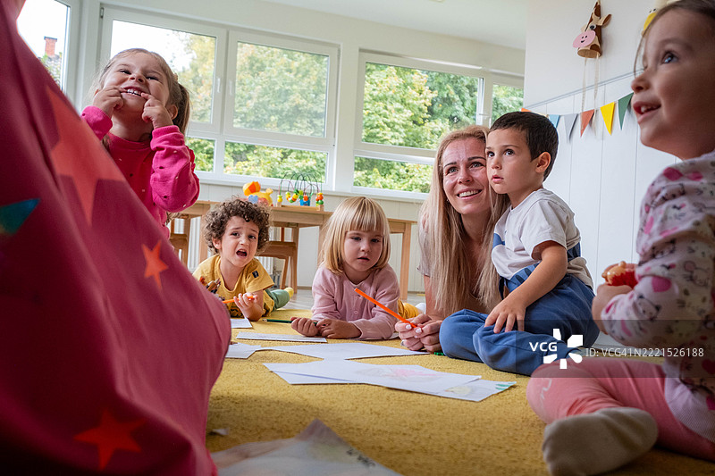 幼儿园的小朋友们躺在地上，正在纸上涂色和画画。图片素材