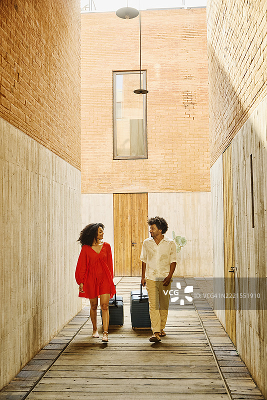 微距镜头下微笑的情侣拖着行李走过酒店走廊图片素材