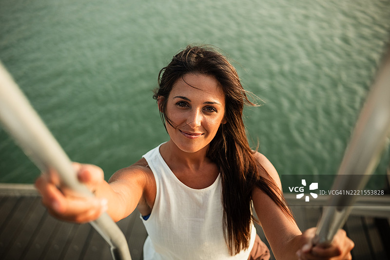 年轻女性在湖边爬梯子图片素材