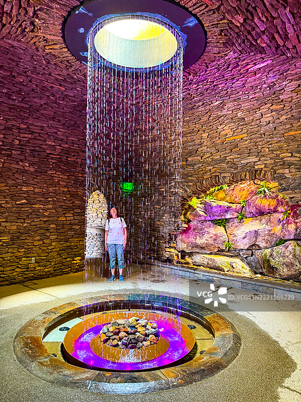 女子在宾夕法尼亚州肯尼特广场的朗伍德花园内的洞穴中凝视着水帘中的圆顶。图片素材