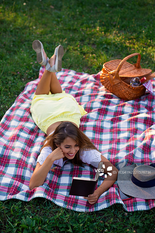 年轻女性在夏季野餐中阅读书籍图片素材