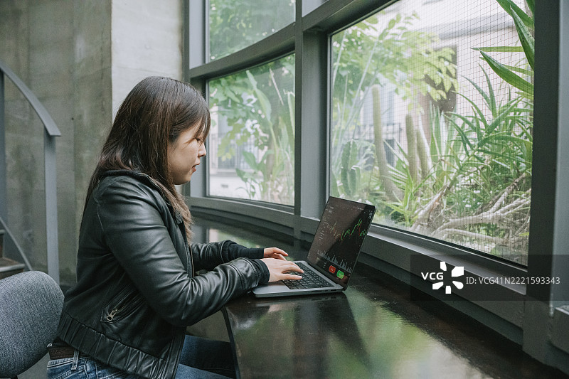 亚洲日本女性在现代工作空间中分析股票市场数据，使用笔记本电脑。图片素材