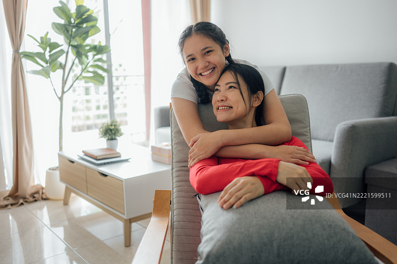 一位亚洲母亲与她的成年女儿相拥而笑的肖像图片素材