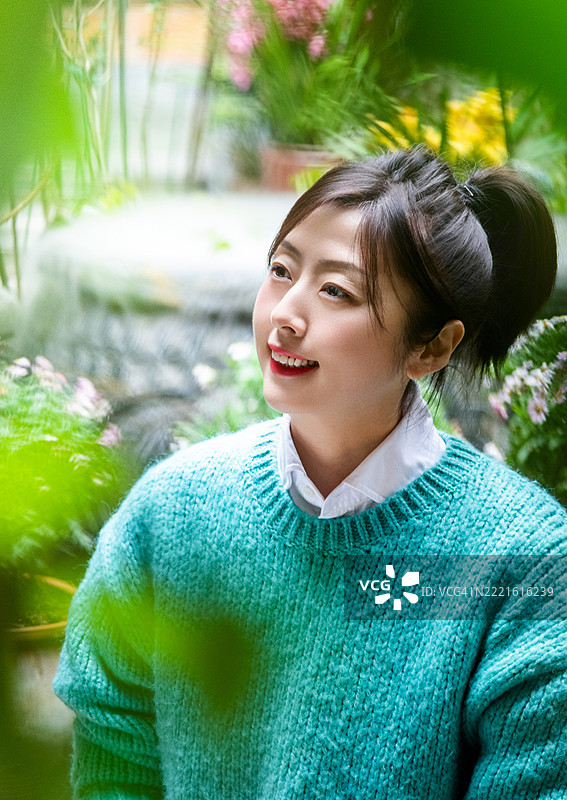 微笑的女性坐在户外，目光投向远方图片素材