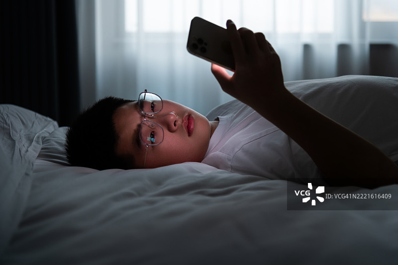 少年男孩躺在床上使用手机图片素材