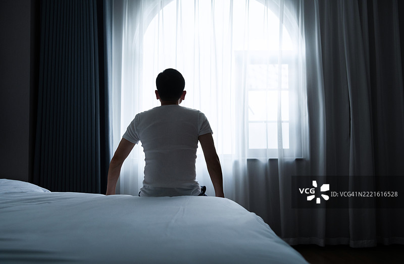 一个男人坐在床上的背影图片素材
