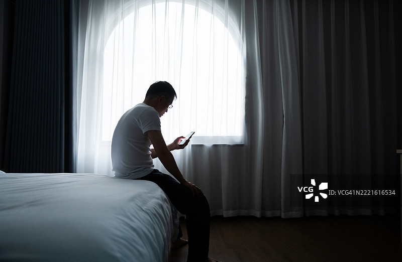 男人坐在床上使用手机图片素材
