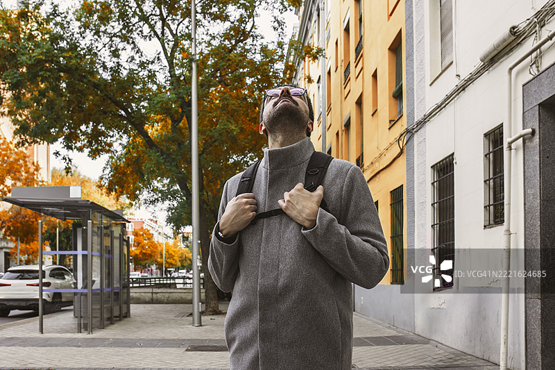 游客在秋天的城市中走路时仰望天空图片素材