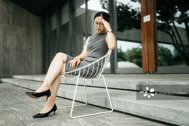 这位亚洲女商人坐在椅子上，神情沉重。图片素材