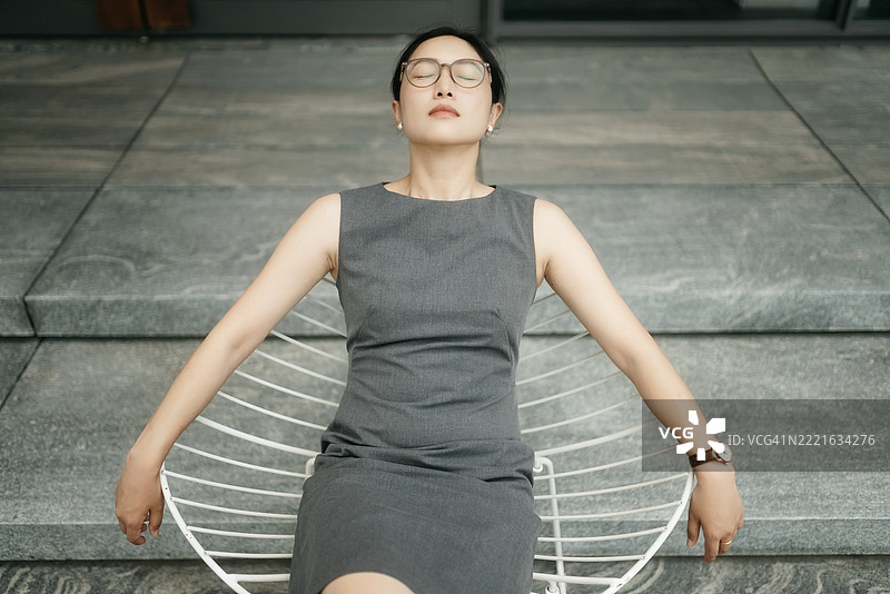 这位亚洲女商人坐在椅子上，神情沉重。图片素材