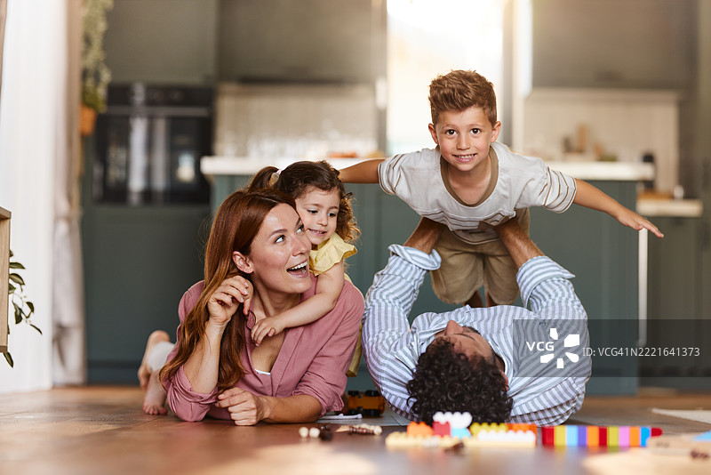 快乐的家庭在家里地板上玩得很开心。图片素材