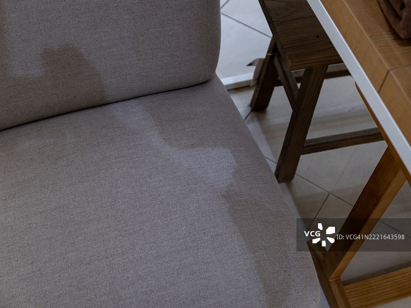 米色布艺椅子旁边的木桌上投射的阴影图片素材