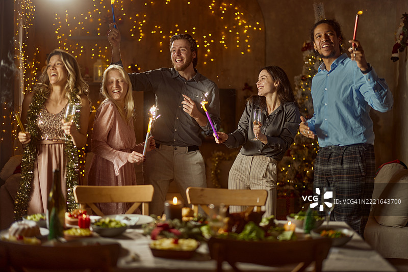 快乐的多元朋友们在家里的圣诞派对上手持火把跳舞。图片素材