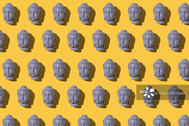 灰色石佛像头部的图案，背景为黄色。佛教，灵性，禅宗，上帝，信仰，和平，宁静，印度和泰国。图片素材